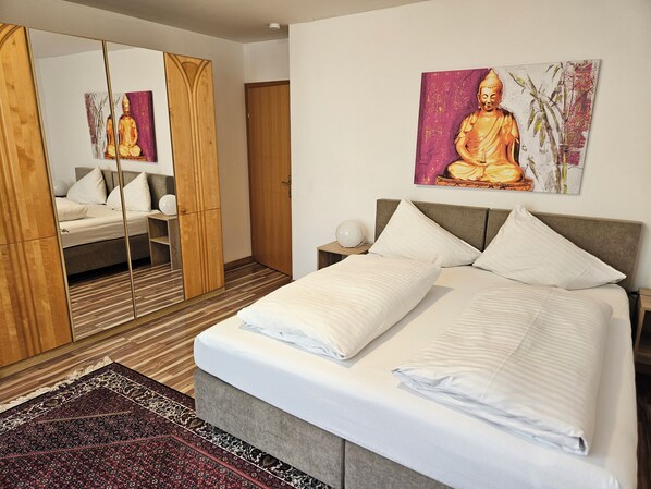 Une chambre moderne avec un grand lit, une armoire et un tableau représentant un Bouddha.