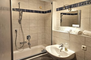 Un baño con bañera, ducha, lavamanos y espejo.