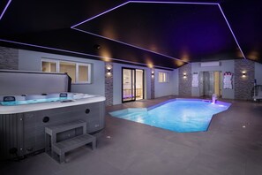 A modern indoor pool area with a hot tub and a stone wall. - Wind Farm (Lytham St. Anne's)