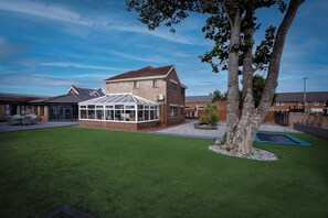 A residential property with a conservatory, a well-maintained lawn, and a trampoline. - Wind Farm (Lytham St. Anne's)