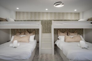 A hotel room with bunk beds, a central staircase, and a textured wall. - Wind Farm (Lytham St. Anne's)