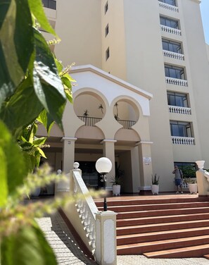 A hotel entrance with a staircase leading up to a gated entrance, a sign indicating a pet-friendly policy, and a person standing on the steps. - Vacation Apartment 'Castle Harbor C118' with Sea View and Wi-Fi (Los Cristianos)