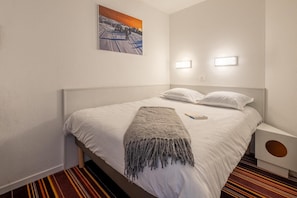 A hotel room with a bed, a throw blanket, a painting on the wall, and a nightstand with a lamp. - 10m from ski slopes, balcony, ski locker, 19-24m², Avoriaz (Avoriaz)