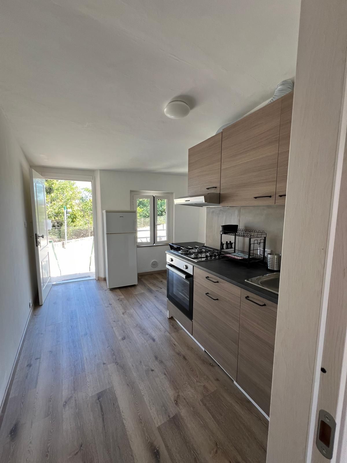 Eine Küche mit Holzschränken, einem Herd und einem Kühlschrank.