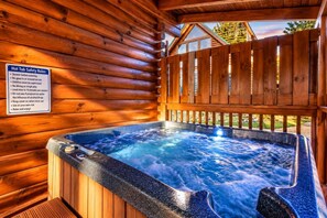 Una cabaña de madera con hidromasaje, un cartel con normas de seguridad y vistas al exterior.