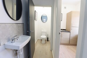 A modern bathroom with a white sink, a toilet, and a mirror. - 5 Woodland Crescent (Manchester)