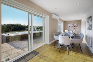 A dining area with a table set for six, a hot tub, and a view of a natural landscape. - Luxury Farmhouse (Chorley)