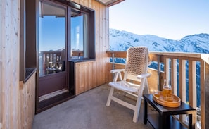 A wooden balcony with a white chair, a table with a tray of drinks, and a view of snow-covered mountains. - 10m from ski slopes, view mountain, balcony, ski locker, 25-35m², Avoriaz (Avoriaz)