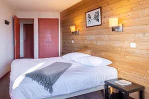 A hotel room with a wooden headboard, a bed with white bedding, a grey throw blanket, two bedside lamps, and a framed picture on the wall. - 10m from ski slopes, view mountain, balcony, ski locker, 25-35m², Avoriaz (Avoriaz)