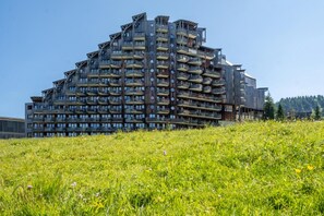 En flervåningsbyggnad med bostäder och balkonger, som reser sig mot en klar himmel.