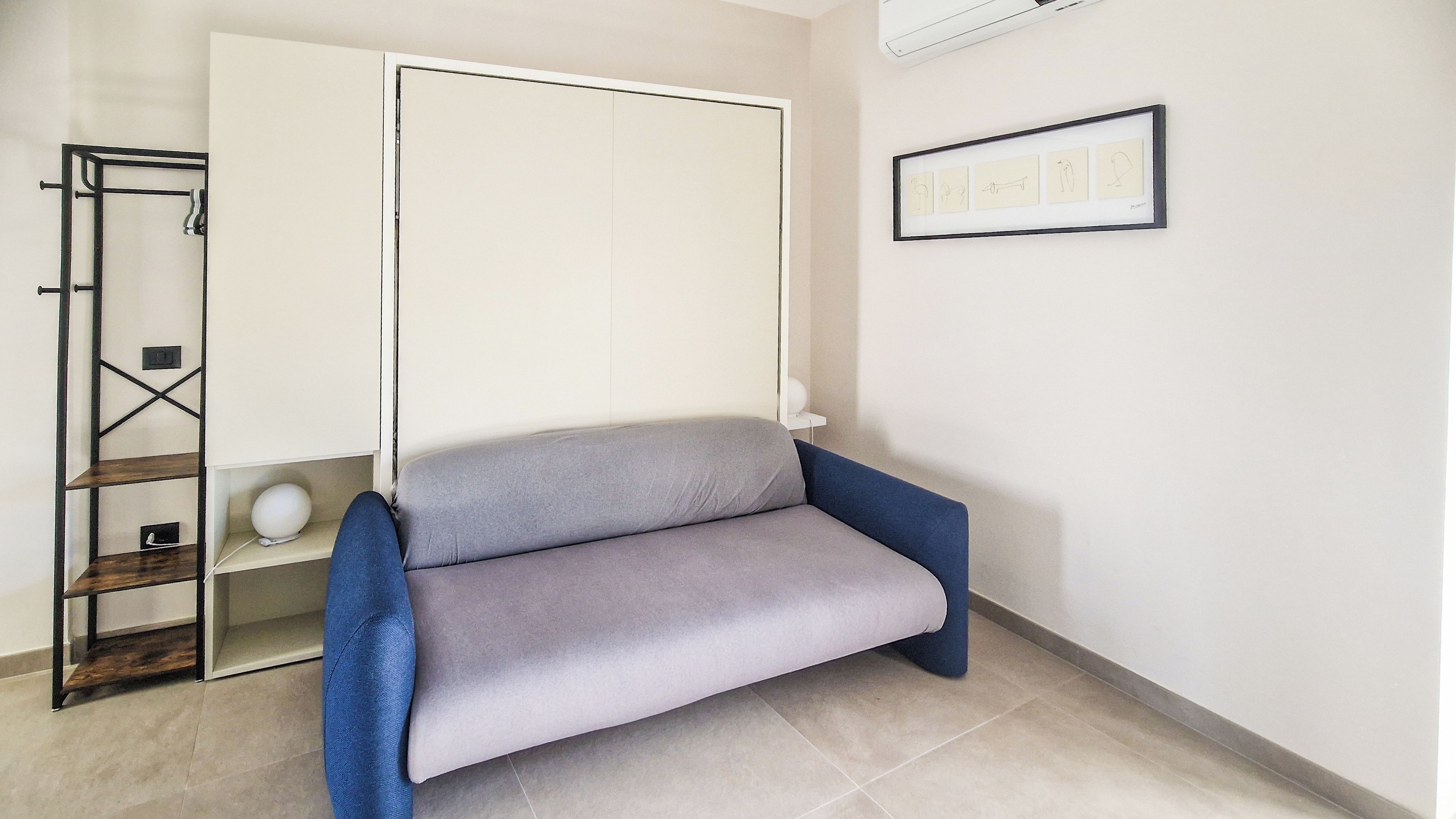 A room with a grey sofa, a white cabinet, and a framed picture on the wall.