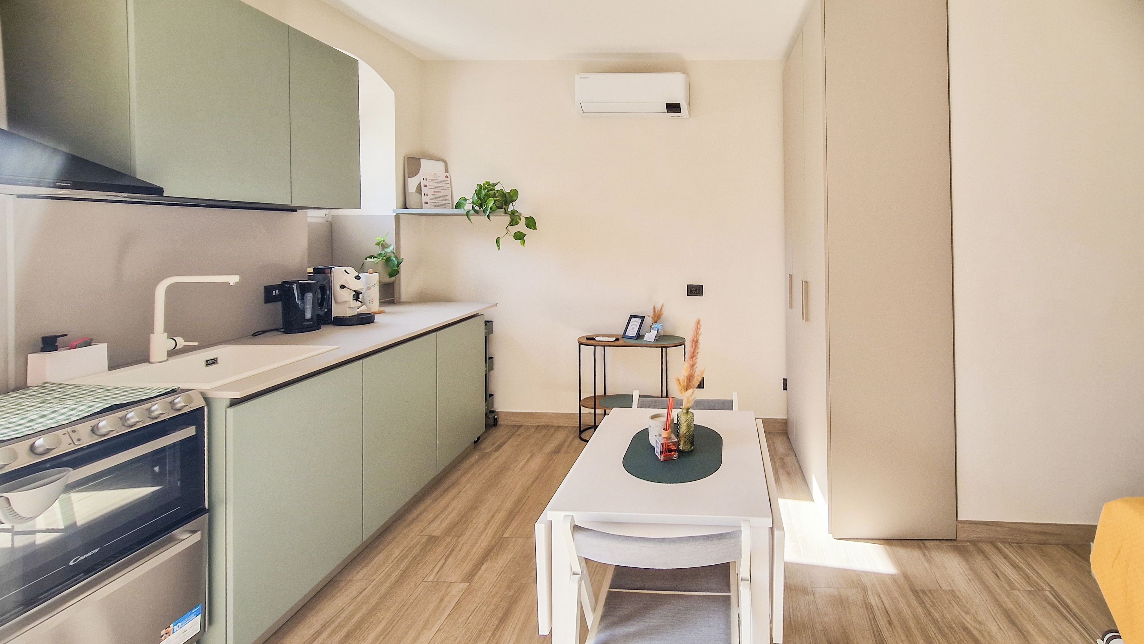Una cocina compacta con horno integrado, cafetera y una pequeña mesa de comedor con sillas.