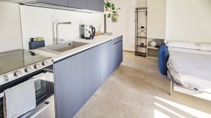 Cocina compacta con estufa, lavamanos y electrodomésticos modernos.