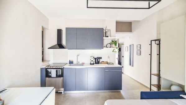 A compact kitchen with grey cabinets, a built-in oven, and a coffee maker.