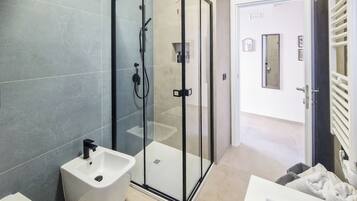 A modern bathroom with a glass-enclosed shower, a white sink, and a towel rack.
