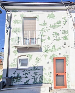 Un edificio con balcón, ventana y puerta.