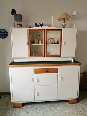 Et hvidt skab med træbordplade, en skuffe og to døre med glas.