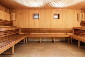 Eine Sauna mit Holzbänken und zwei kleinen Fenstern.