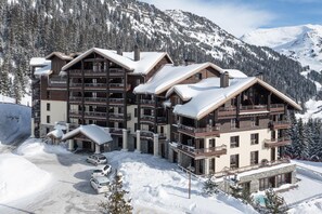 A multi-story hotel with balconies, a ski lift, and a snowy mountain backdrop. - Wifi, 5m from ski slopes, swimming pool, sauna, hammam, balcony, ski locker, 35m², Flaine (Arâches-la-Frasse)