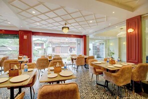 A hotel dining area with tables set for four, chairs, and a chandelier. - Palette Boragaon Formerly Midtown Inn (Guwahati)