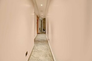 A hallway with a marble floor and light-colored walls. - Palette Boragaon Formerly Midtown Inn (Guwahati)