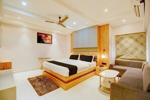 A modern bedroom with a bed, bedside table, and a small round table. - Palette Boragaon Formerly Midtown Inn (Guwahati)