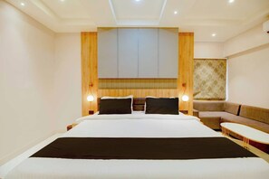 A hotel room with a large bed, a sofa, and a small table. - Palette Boragaon Formerly Midtown Inn (Guwahati)