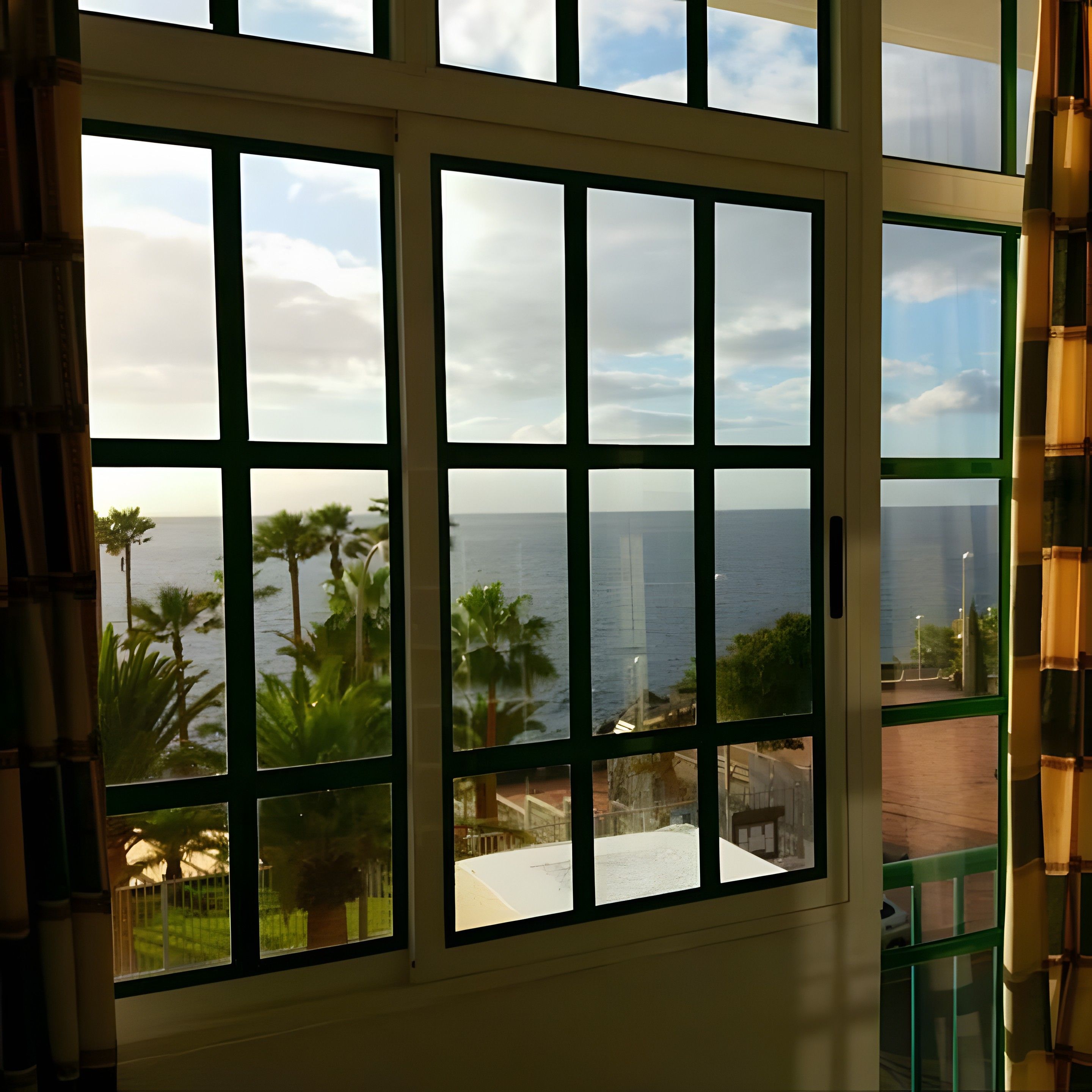 A view through a window with a grid pattern, overlooking a body of water and palm trees.