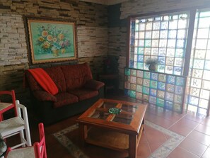 Ein Wohnzimmer mit Backsteinwand, einem roten Sofa, einem Holztisch und einem großen Fenster mit bunten Glasscheiben.