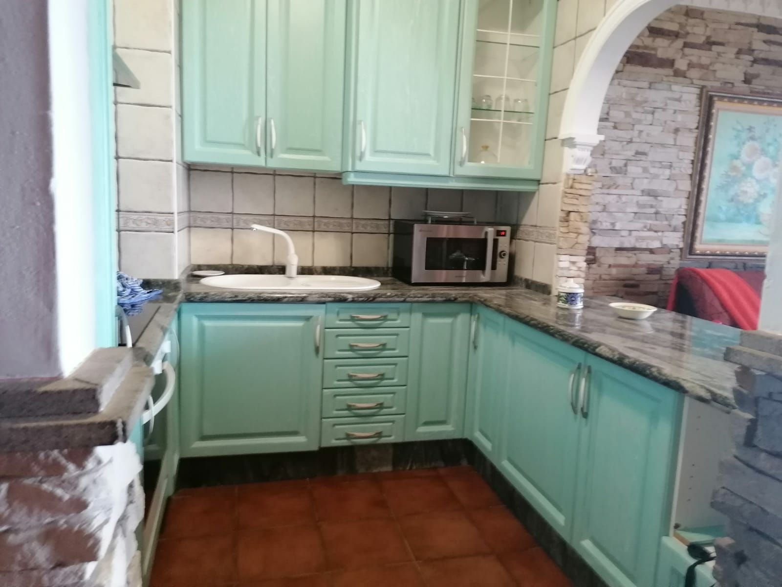 Una cocina con armarios azul turquesa, un microondas y un lavabo.