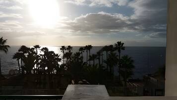Un balcón con vista al mar y palmeras.