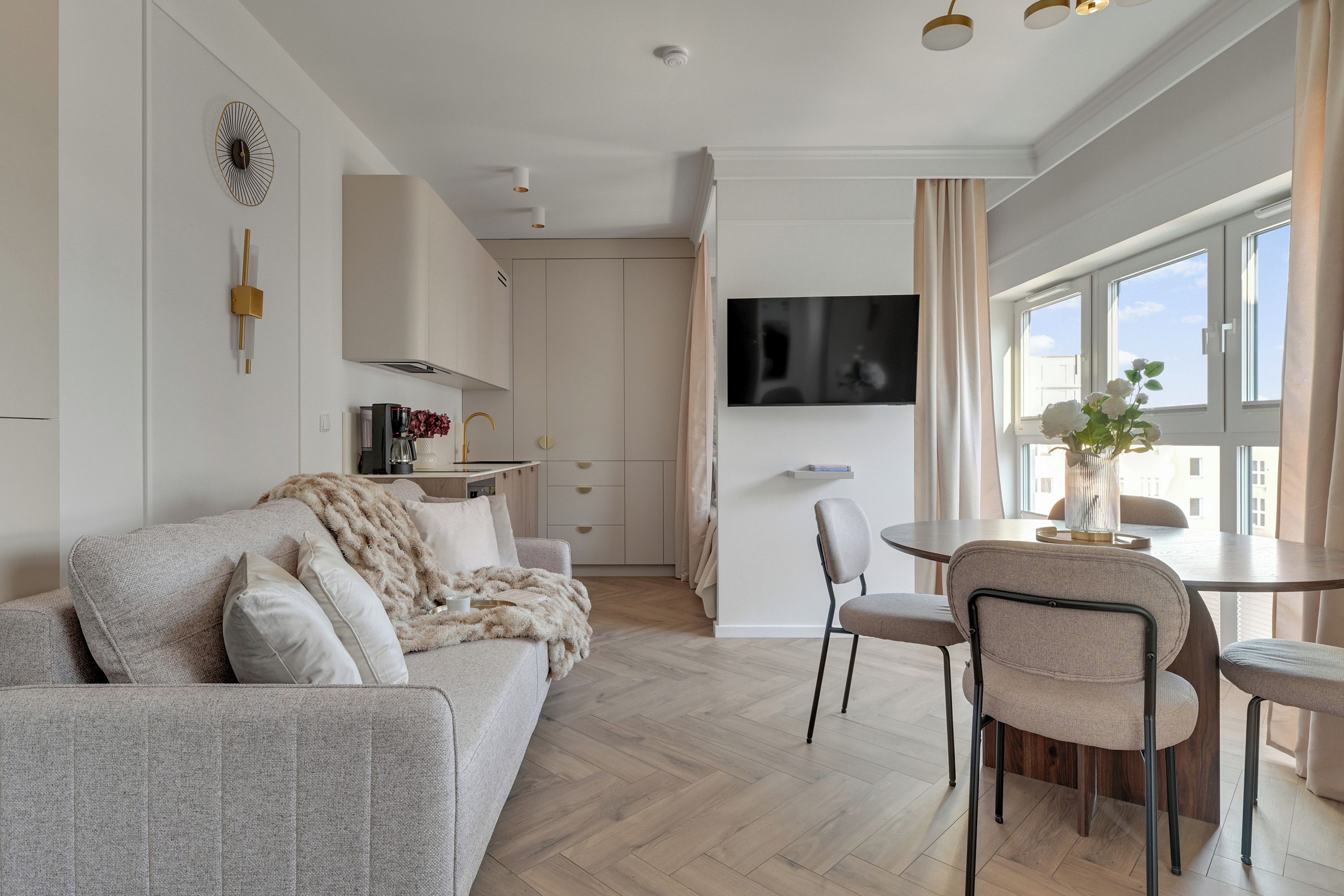 Un salon moderne comprenant un canapé, des fauteuils, une table à manger et un téléviseur fixé au mur.
