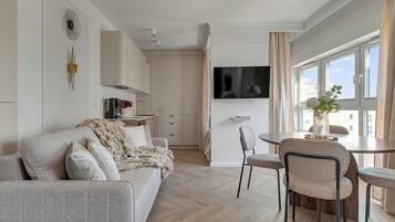 Un salon moderne comprenant un canapé, des fauteuils, une table à manger et un téléviseur fixé au mur.