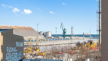 Udsigt over en havn med industriområde, kraner og et skib i baggrunden.