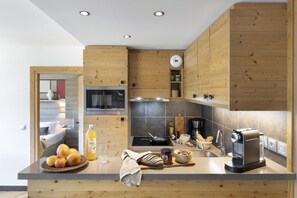Eine moderne Küche mit Holzschränken, einer eingebauten Mikrowelle, einem Herd und einer Kaffeemaschine.