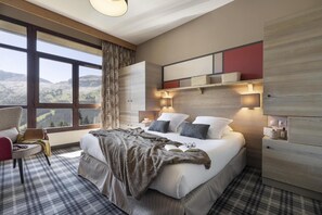 A modern bedroom with a large bed, a seating area, and a view of the outdoors. - Wifi, 5m from ski slopes, view mountain, swimming pool, sauna, hammam, balcony, ski locker, 75m² (Arâches-la-Frasse)