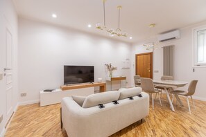 A modern living room with a sofa, a TV, and a dining area with chairs and a table. - Classic Prati Living (Rome)