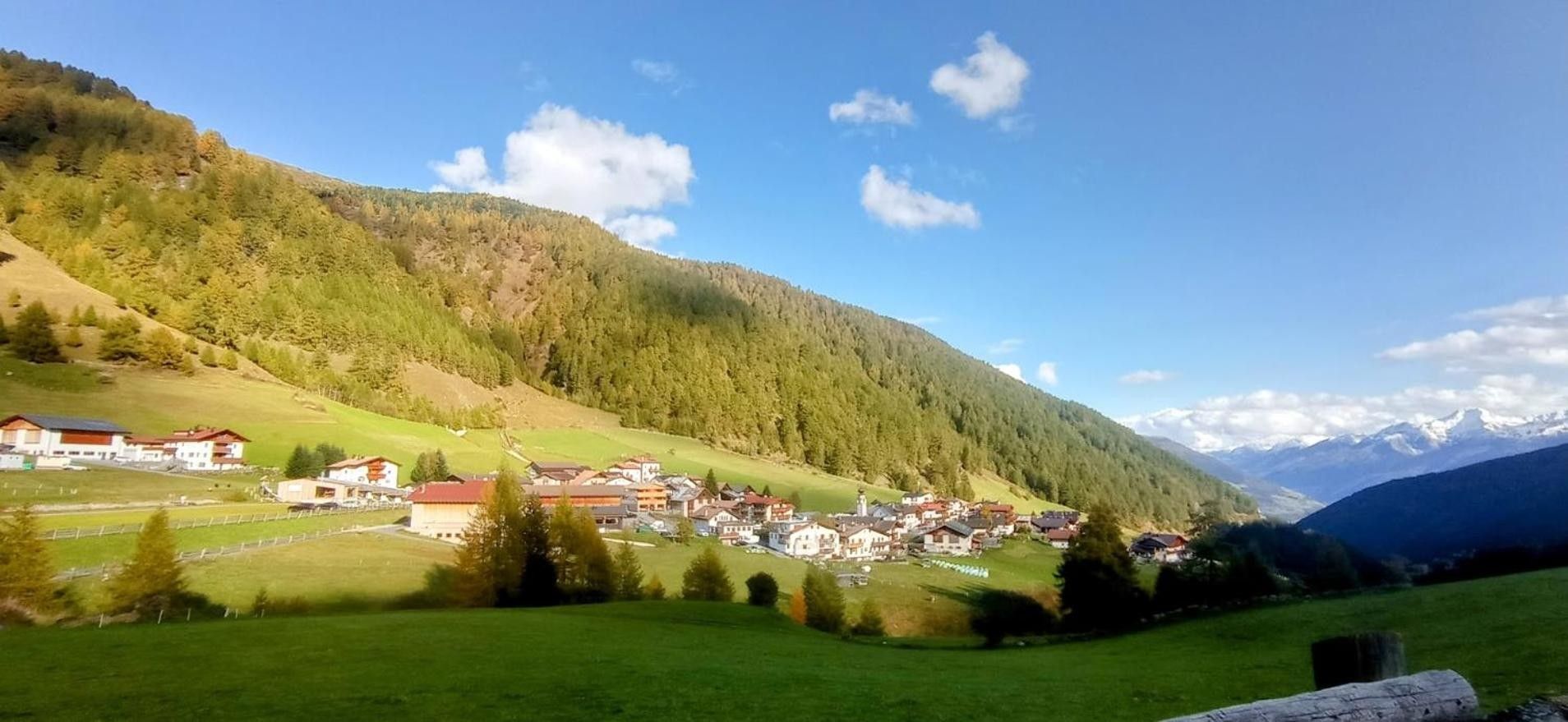 Ein Dorf eingebettet in ein Tal mit Häusern und einer Bergkulisse.