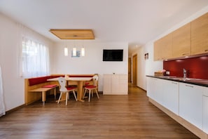 Una cucina moderna con mobili in legno, un tavolo da pranzo con sedie e una parete decorata in rosso.