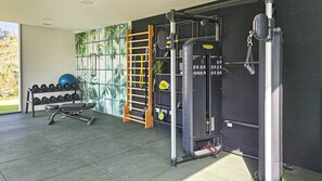 Een sportschool met fitnessapparatuur, een squatrek aan de muur en een dumbbellsrek.