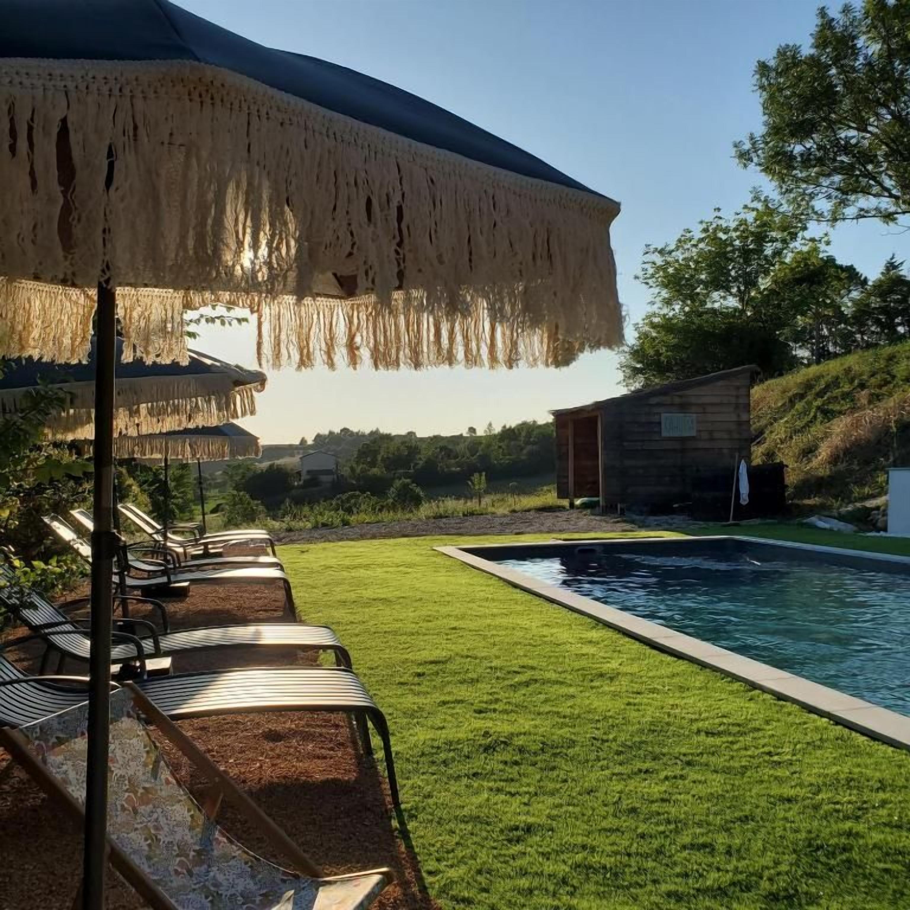 Zona de piscina con sillones de descanso y un espacio de estar techado.