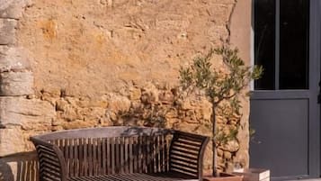 A stone wall, a wooden bench, a potted plant, and a door.