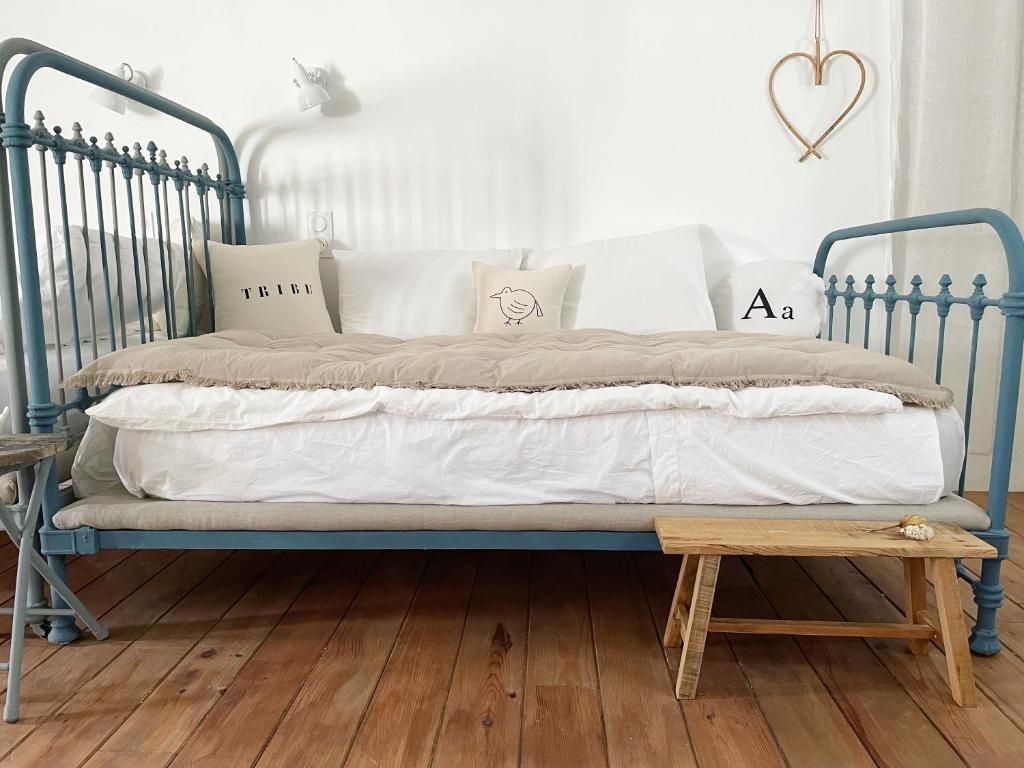 A bed with a blue metal frame, white bedding, and a small wooden table beside it.