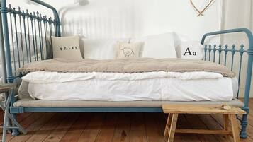 A bed with a blue metal frame, white bedding, and a small wooden table beside it.