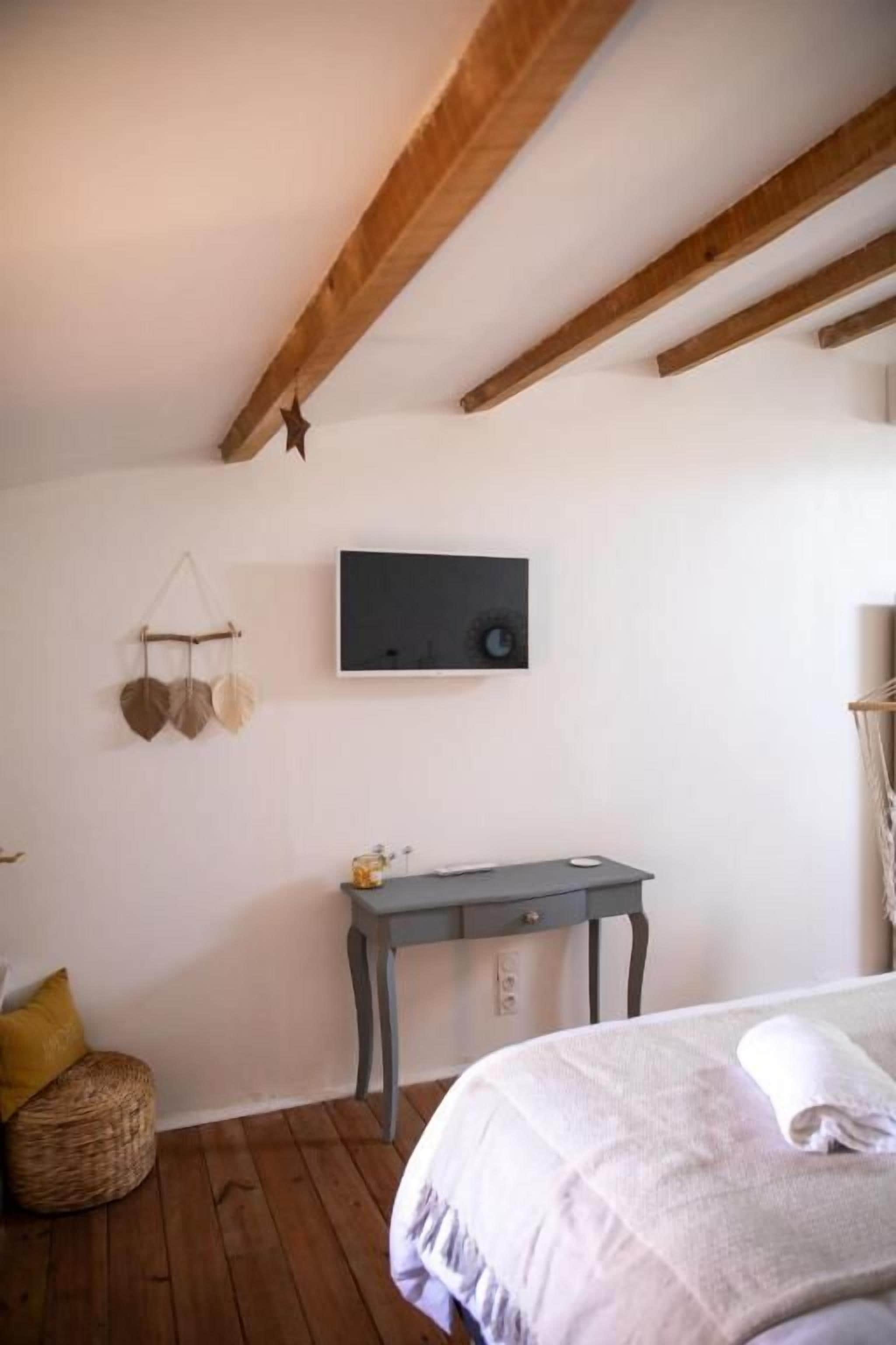 Une chambre à coucher avec un lit, un bureau et un téléviseur fixé au mur.