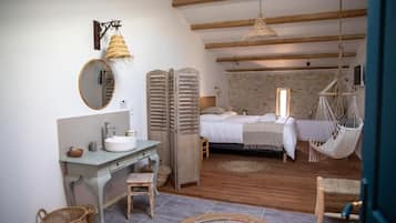 A bedroom with a bed, a hanging chair, a bedside table, and a mirror.