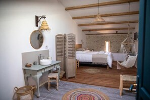 Une chambre à coucher avec un lit, un fauteuil suspendu, une table de chevet et un miroir.