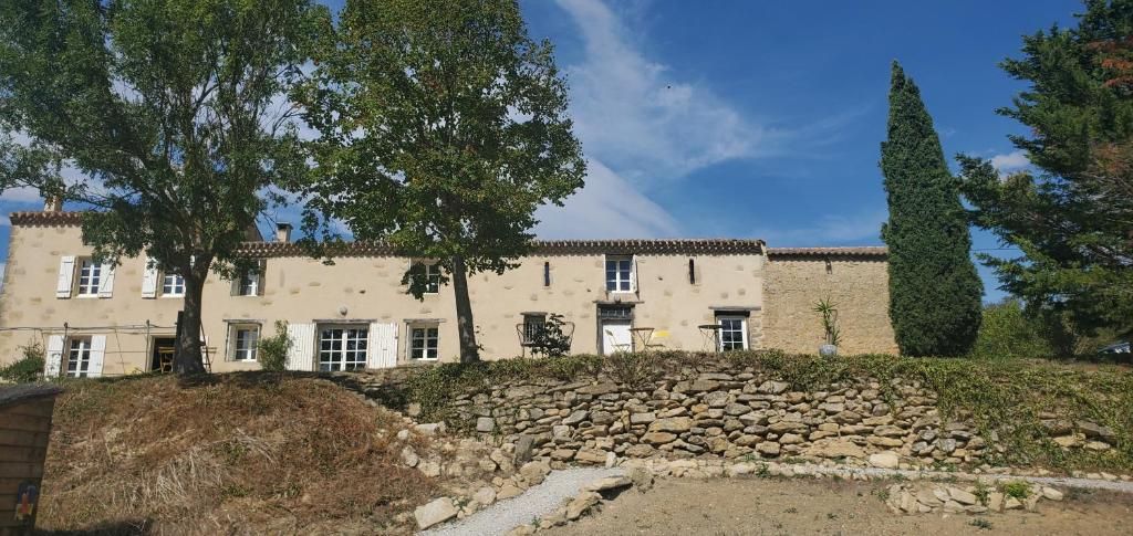 A building with a stone wall and a tree in front.