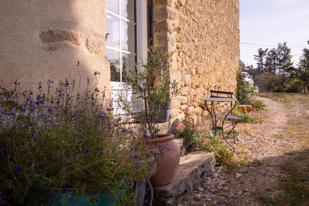 A rustic stone building with a bench and potted plants outside.