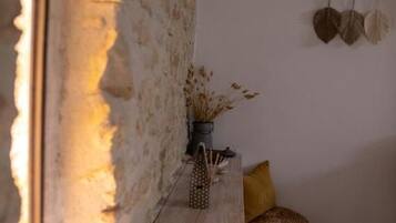 A rustic interior with a wooden bench, a stone wall, and a hanging light fixture.